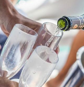 destination wedding pouring champagne on a private yacht tour for weddings in riviera maya, mexico